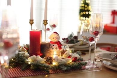 Photo of Christmas place setting with festive decor on wooden table in room