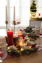 Photo of Christmas place setting with festive decor on wooden table in room