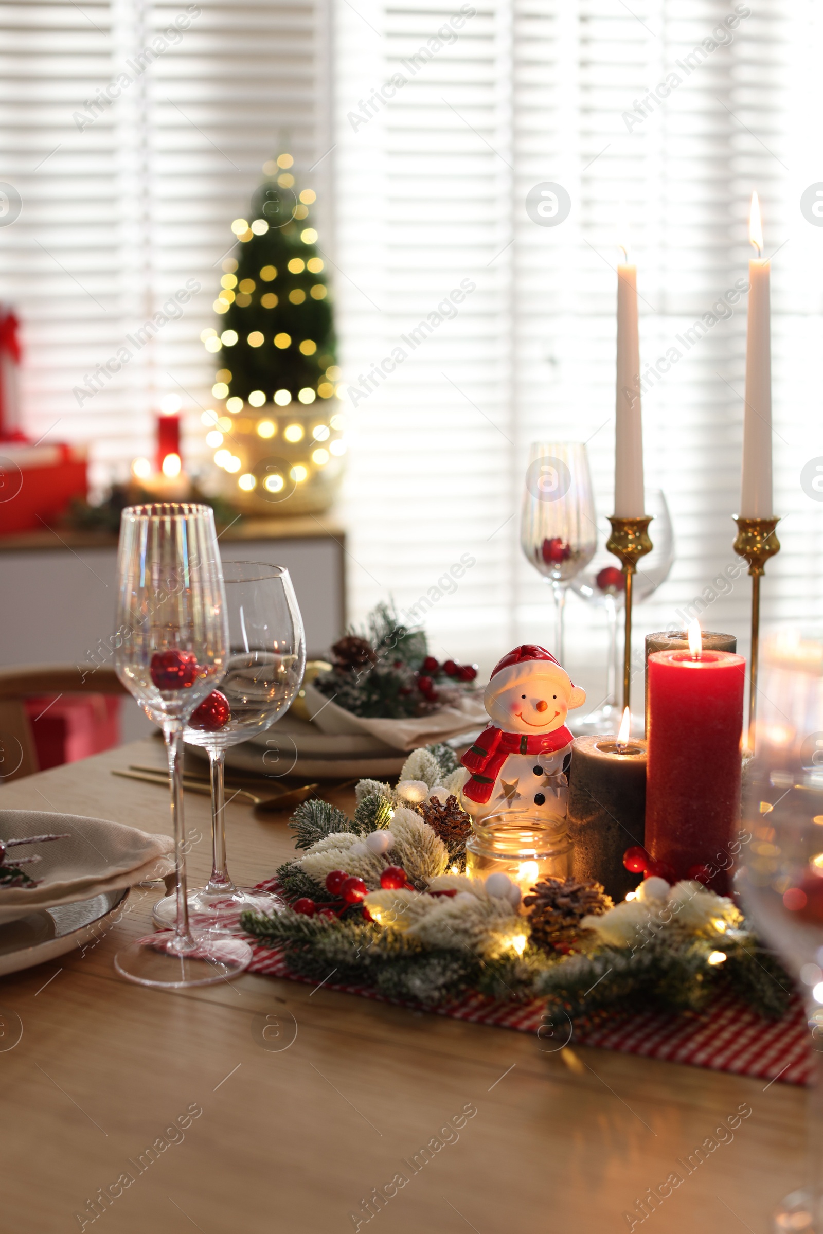 Photo of Christmas place setting with festive decor on wooden table in room