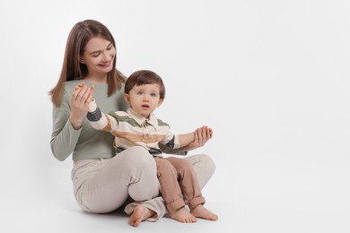 Happy mother with her cute little son on white background, space for text