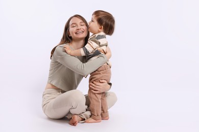 Happy mother with her cute little son on white background, space for text