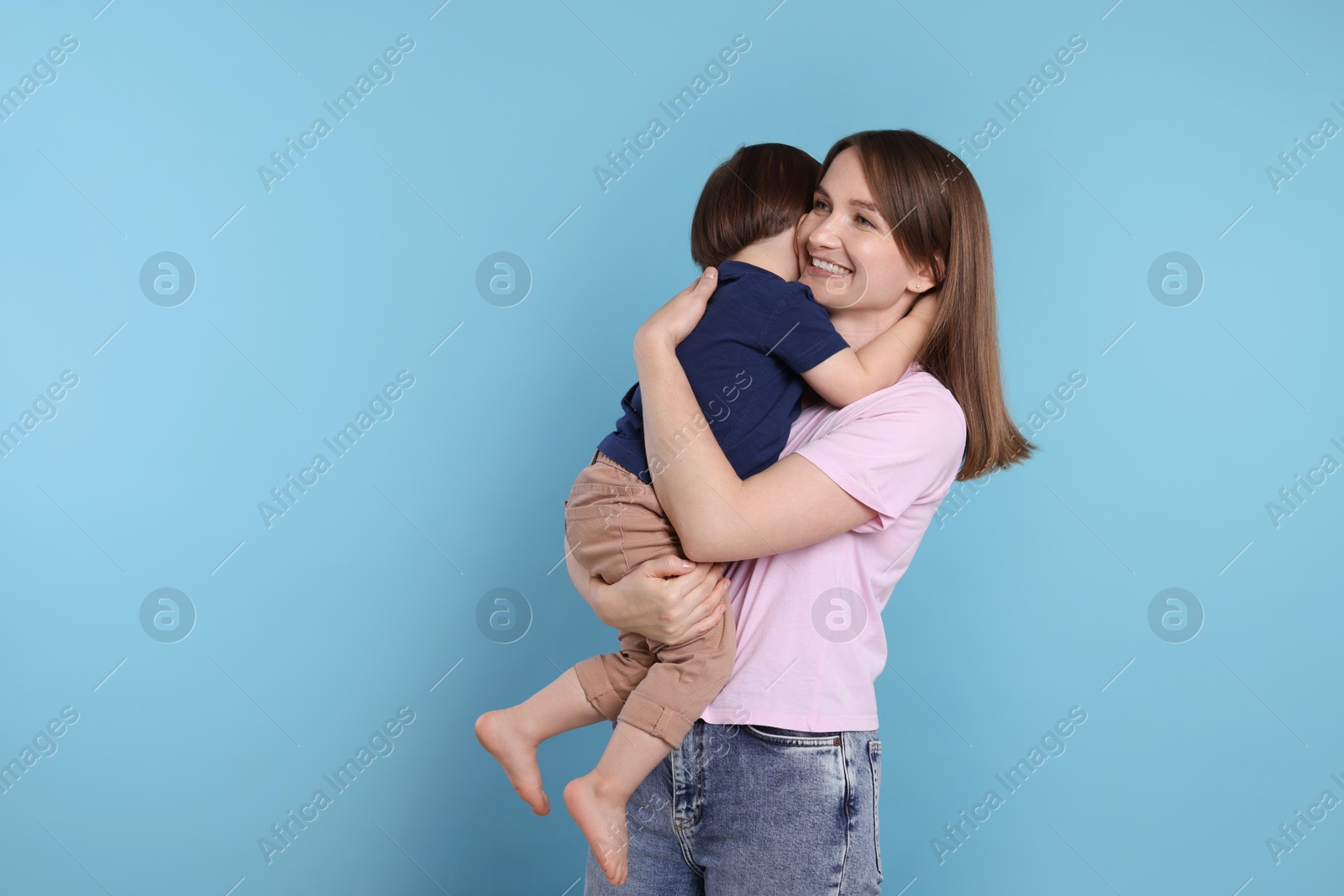 Photo of Happy mother with her cute little son on light blue background, space for text