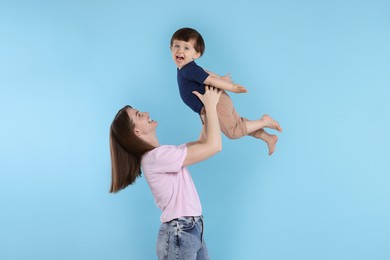 Photo of Happy mother having fun with her cute little son on light blue background