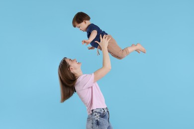 Photo of Happy mother having fun with her cute little son on light blue background