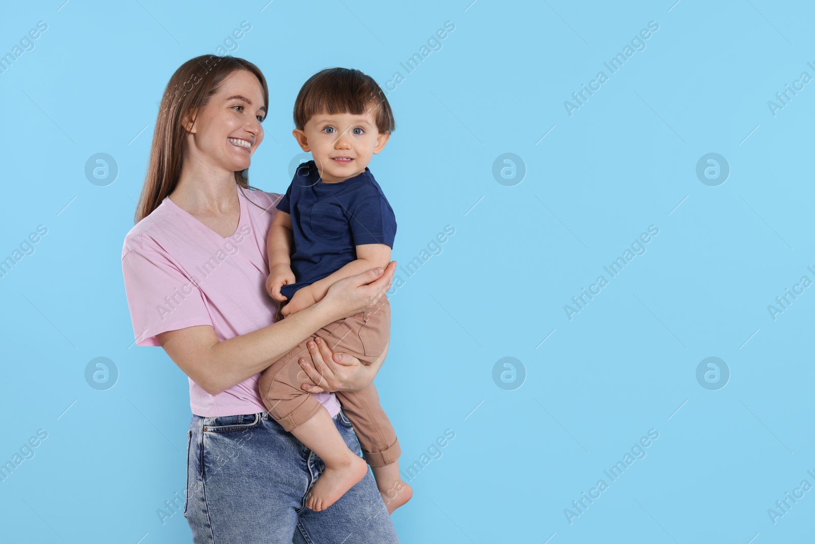 Photo of Happy mother with her cute little son on light blue background, space for text