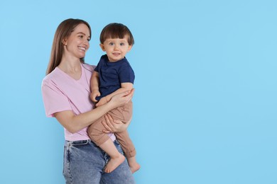 Photo of Happy mother with her cute little son on light blue background, space for text