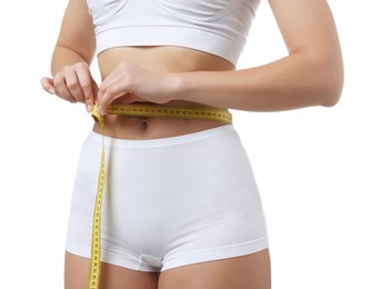 Photo of Weight loss. Woman measuring her slim waist with tape on white background, closeup