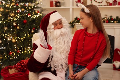 Photo of Christmas celebration. Santa Claus and girl at home