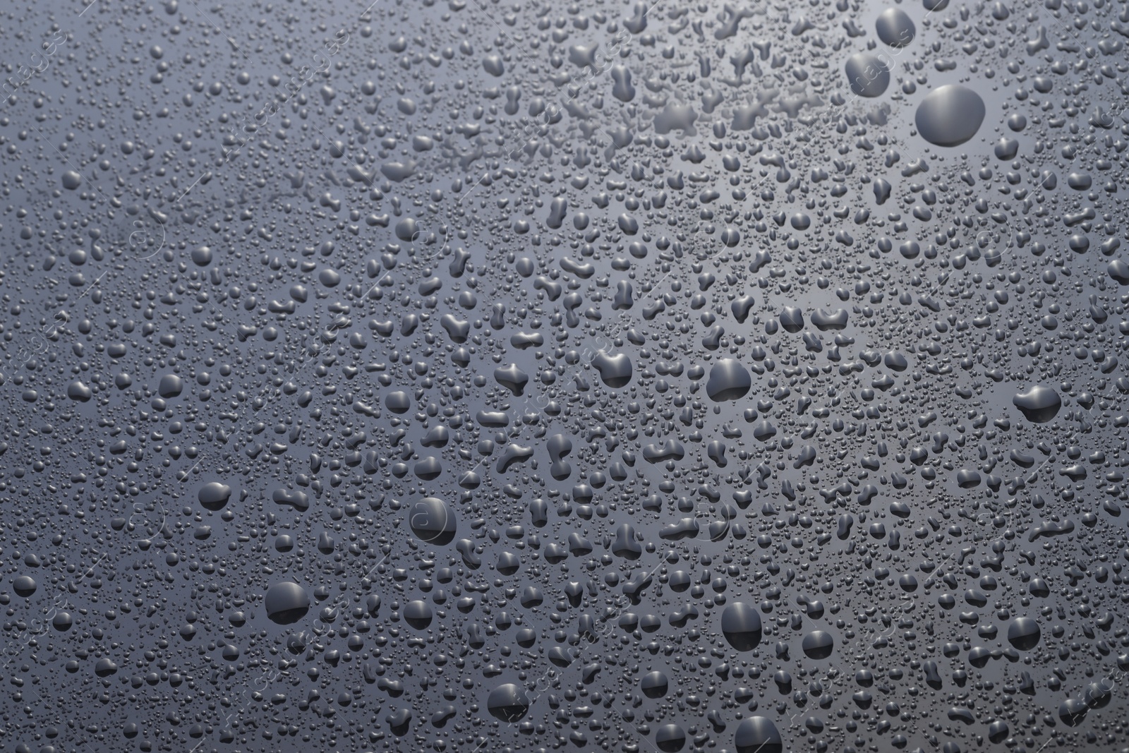 Photo of Water drops on grey glass surface, top view