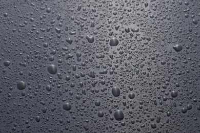 Photo of Water drops on grey glass surface, top view