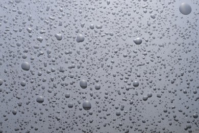 Photo of Water drops on grey glass surface, top view