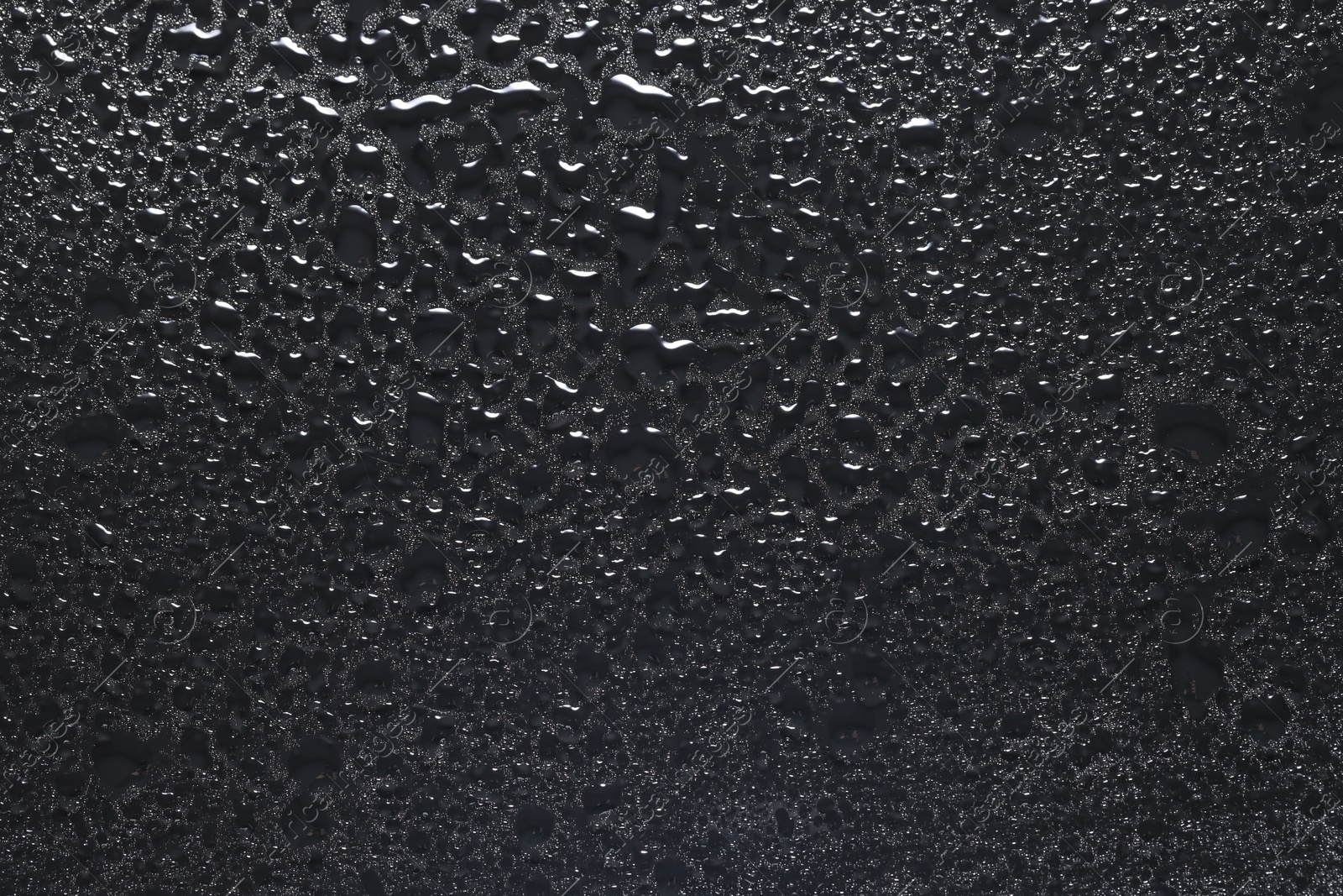 Photo of Water drops on dark grey glass surface, top view