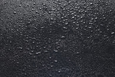 Water drops on dark grey glass surface, top view