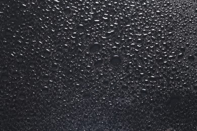 Water drops on dark grey glass surface, top view