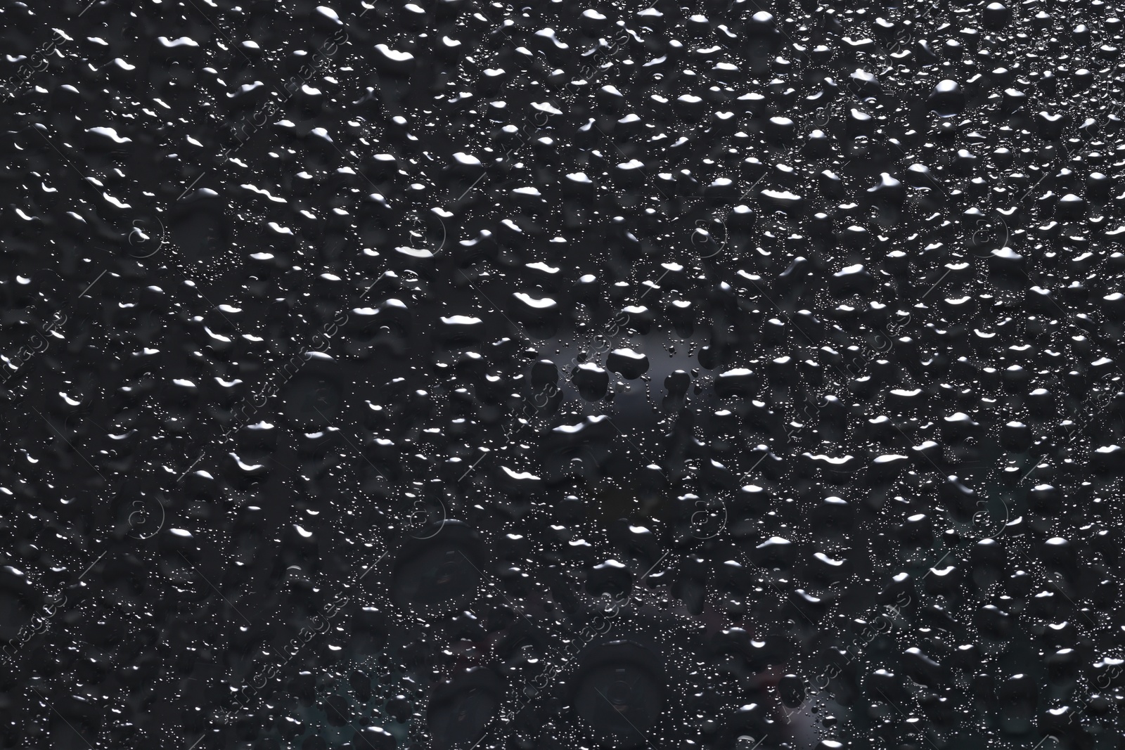 Photo of Water drops on dark grey glass surface, top view