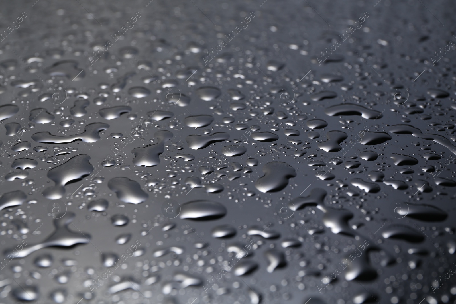 Photo of Water drops on grey glass surface, closeup