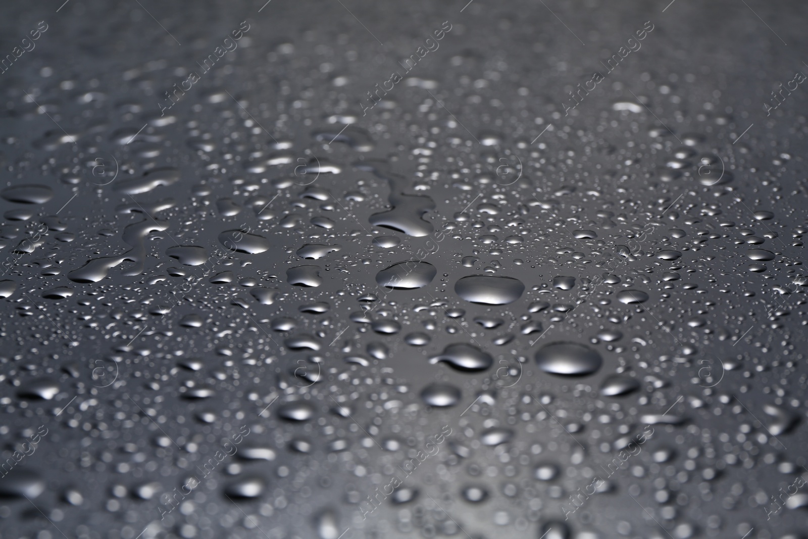 Photo of Water drops on grey glass surface, closeup