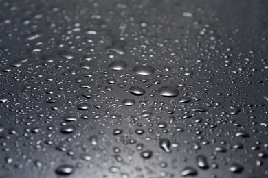 Photo of Water drops on grey glass surface, closeup