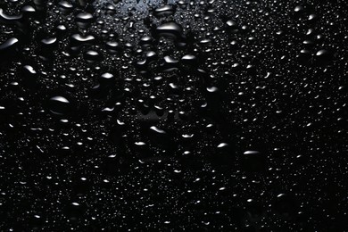 Photo of Water drops on black glass surface, top view