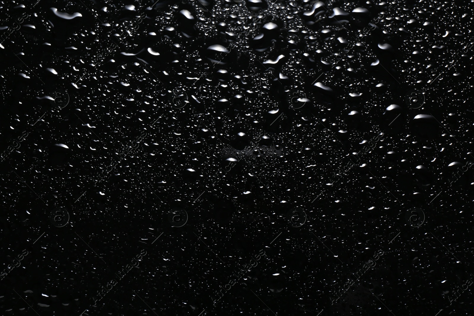 Photo of Water drops on black glass surface, top view