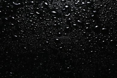 Photo of Water drops on black glass surface, top view