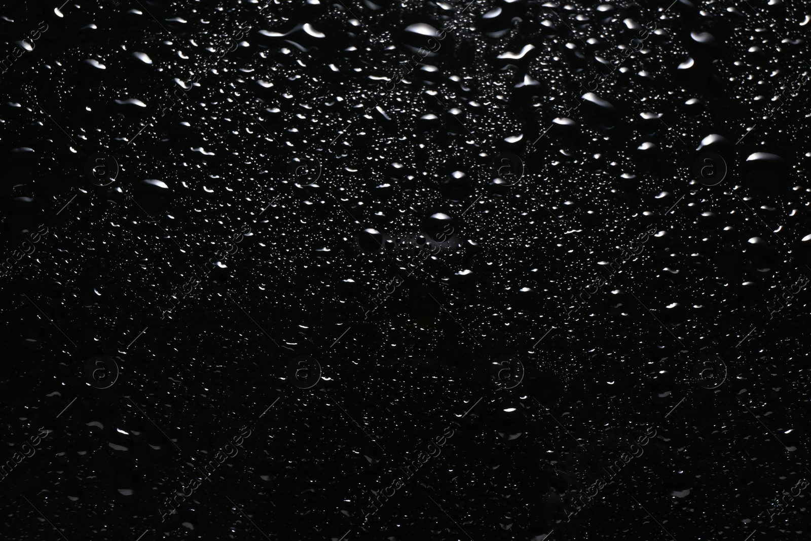 Photo of Water drops on black glass surface, top view