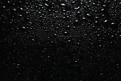 Photo of Water drops on black glass surface, top view