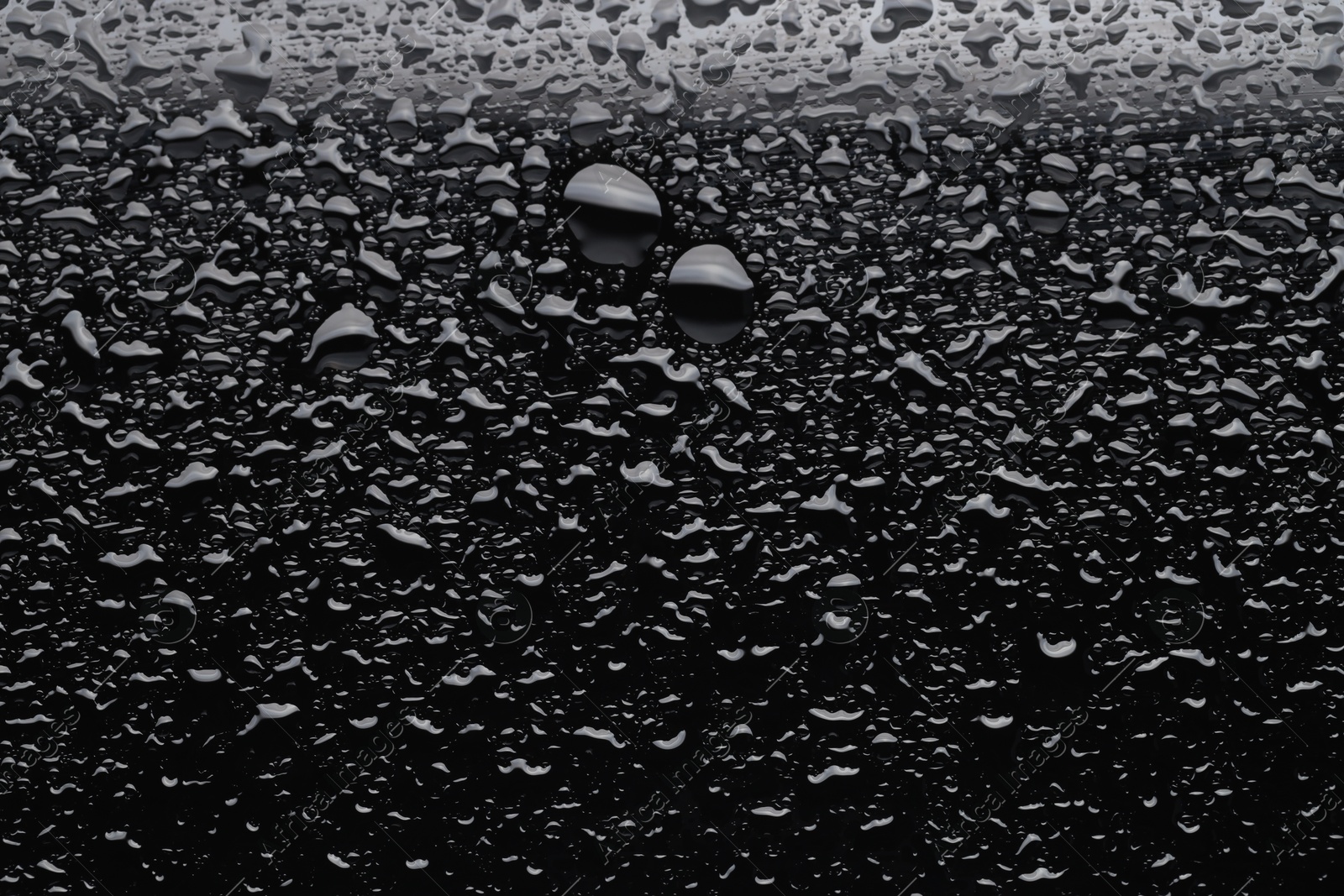 Photo of Water drops on black glass surface, top view