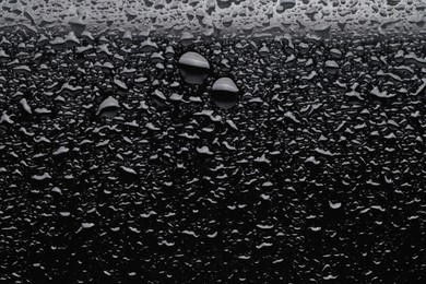 Water drops on black glass surface, top view