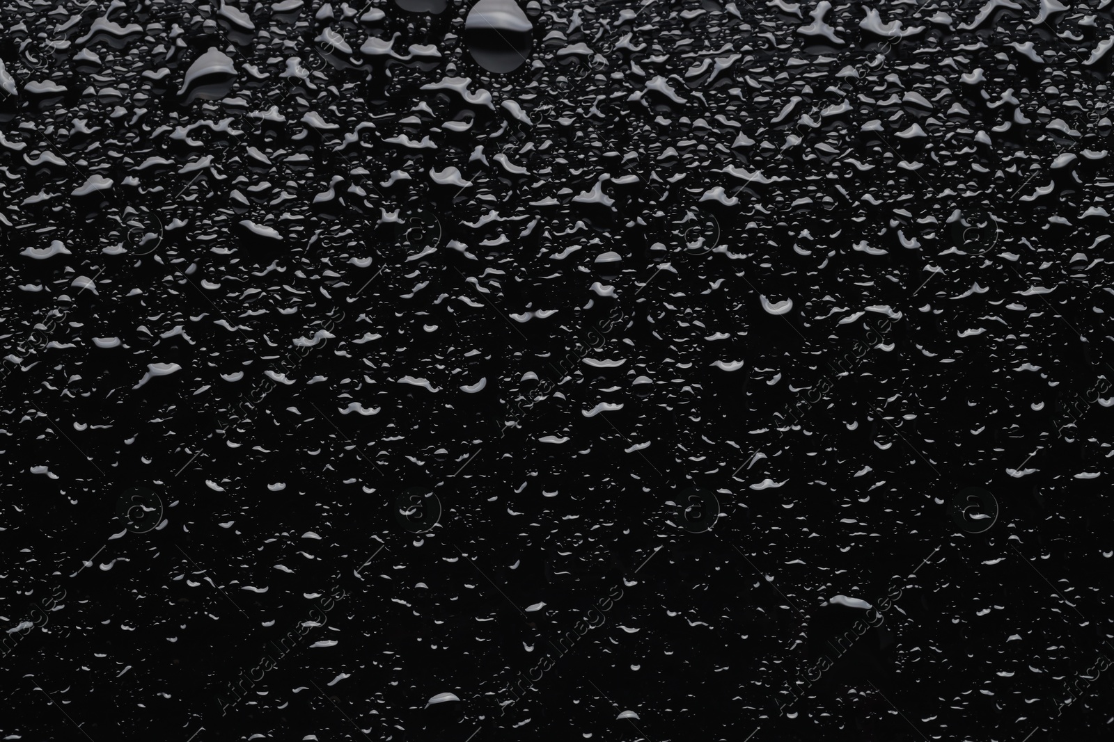 Photo of Water drops on black glass surface, top view