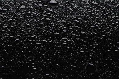 Photo of Water drops on black glass surface, top view