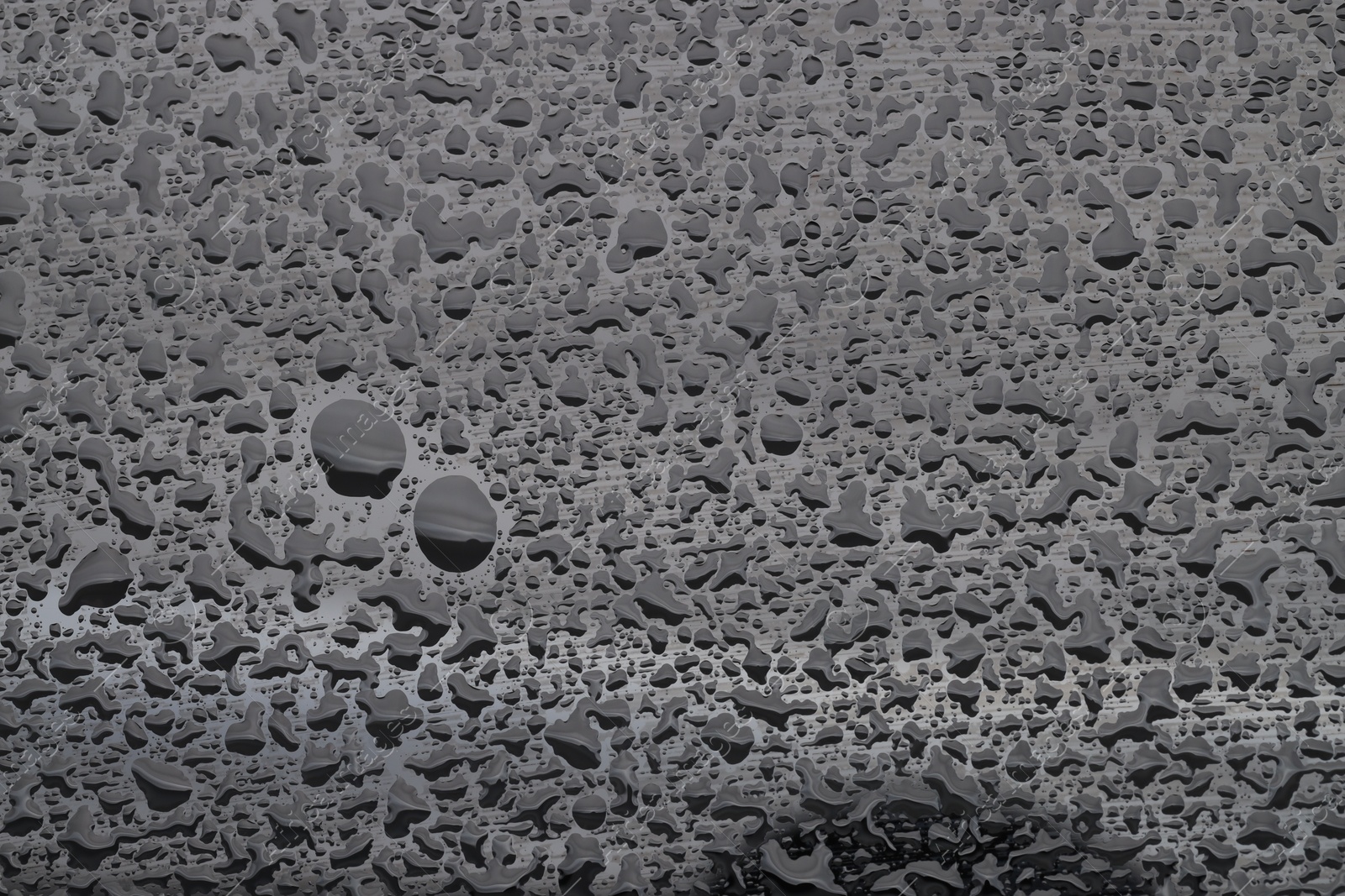 Photo of Water drops on grey glass surface, top view