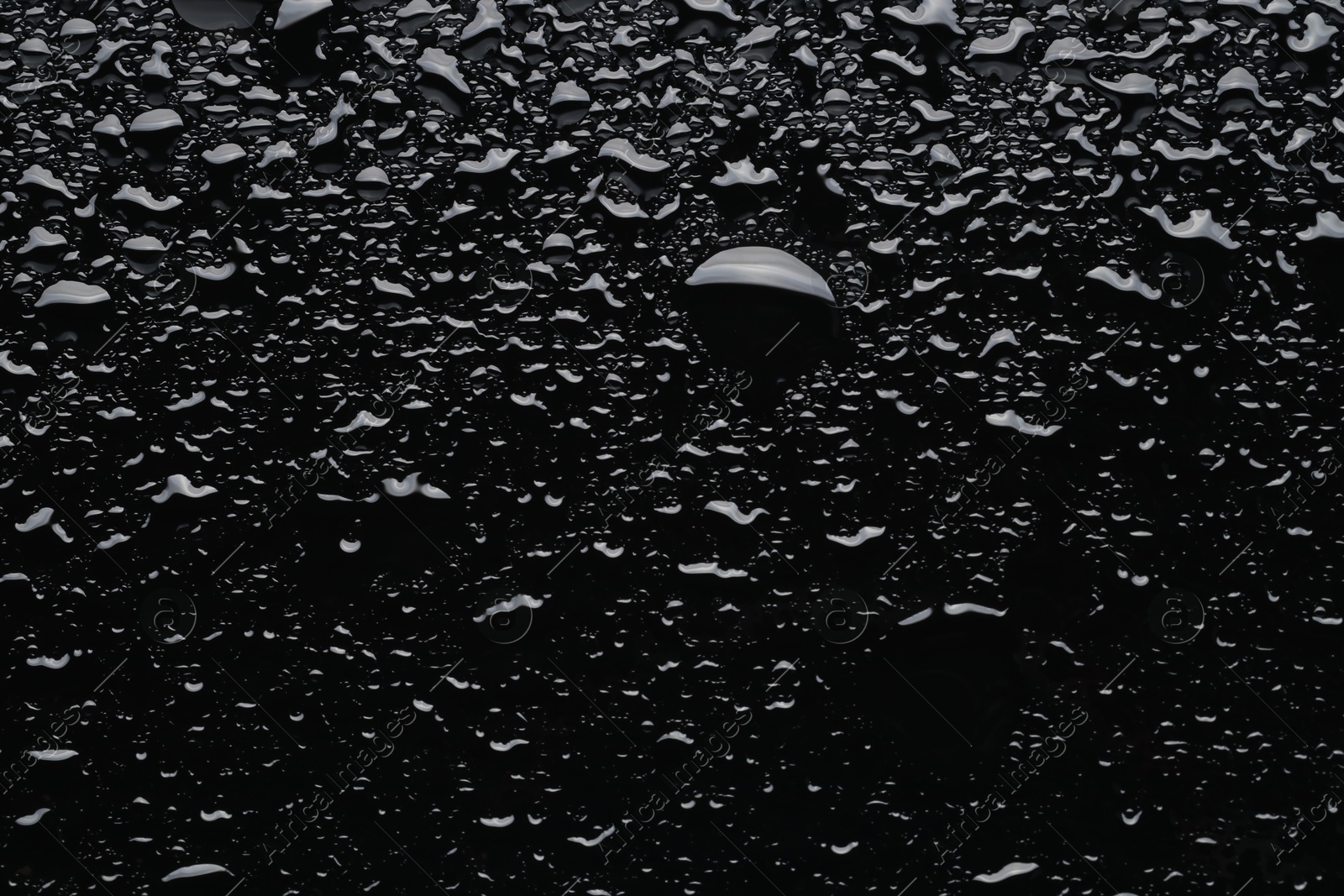 Photo of Water drops on black glass surface, top view