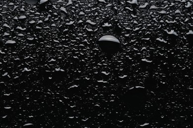 Photo of Water drops on black glass surface, top view