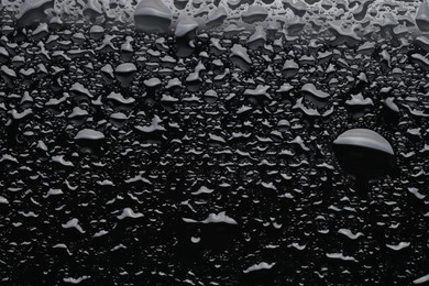 Water drops on black glass surface, top view