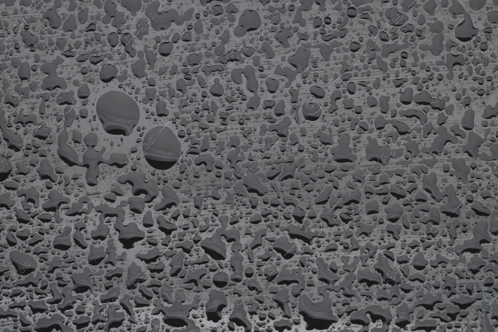 Photo of Water drops on grey glass surface, top view