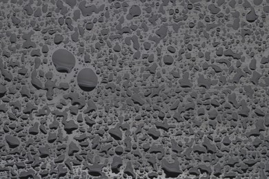 Water drops on grey glass surface, top view