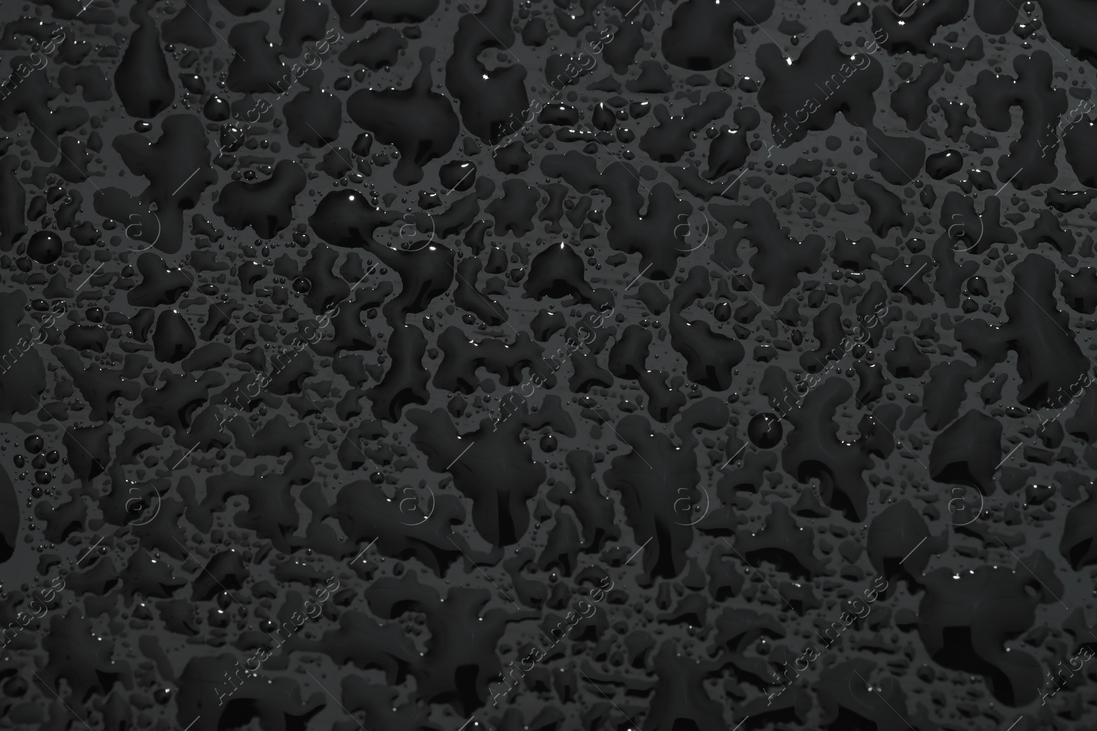 Photo of Water drops on dark grey glass surface, top view