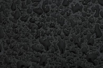 Water drops on dark grey glass surface, top view