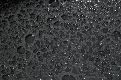 Photo of Water drops on grey glass surface, top view