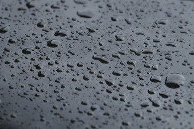 Photo of Water drops on grey glass surface, closeup