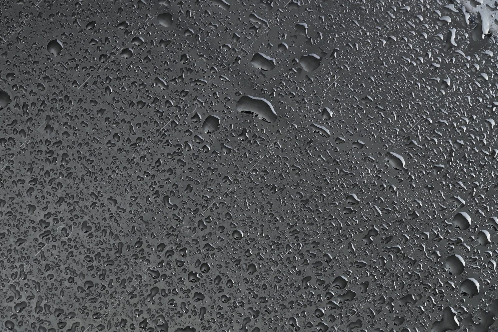 Photo of Water drops on grey glass surface, top view