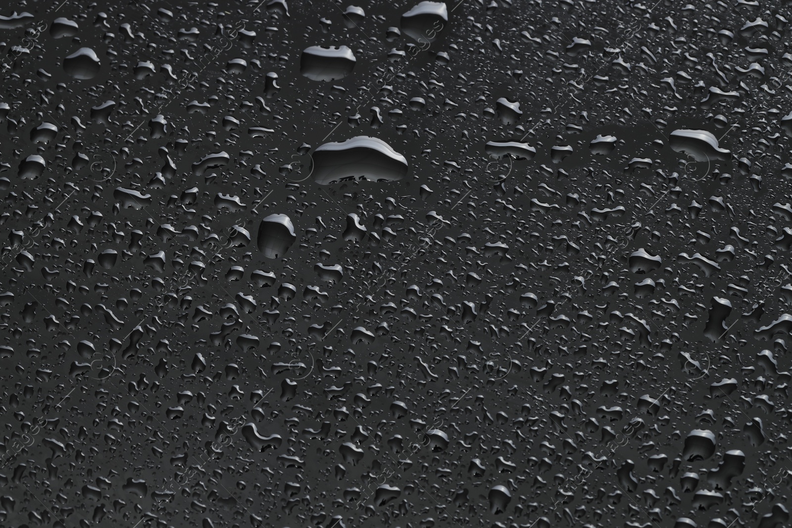 Photo of Water drops on dark grey glass surface, top view