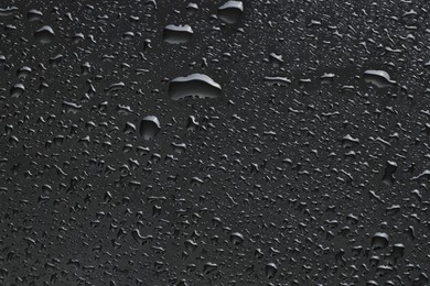 Water drops on dark grey glass surface, top view