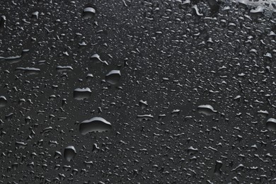 Water drops on dark grey glass surface, top view