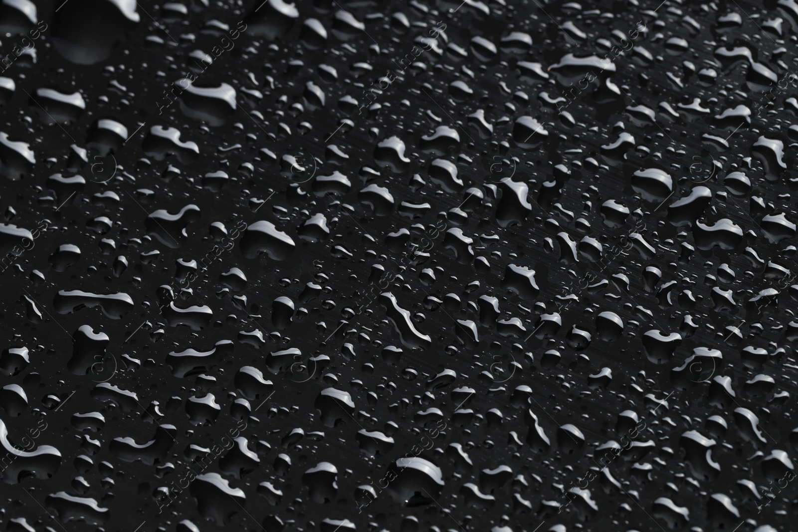 Photo of Water drops on black glass surface, closeup