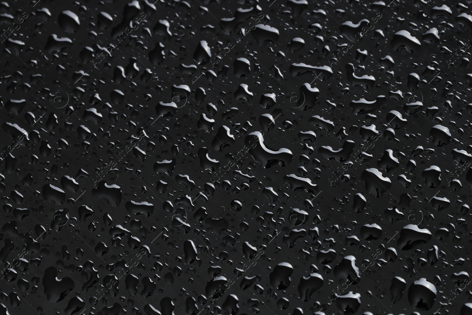 Photo of Water drops on black glass surface, closeup