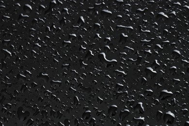 Water drops on black glass surface, closeup