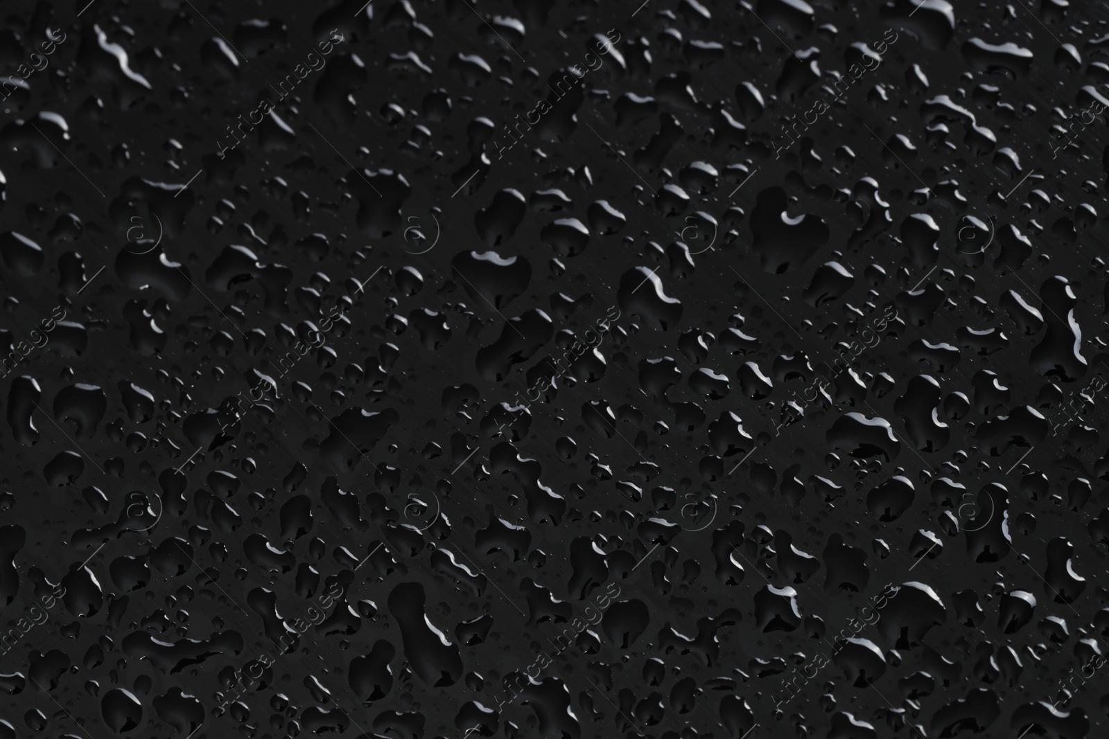 Photo of Water drops on black glass surface, closeup