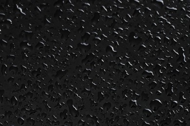 Water drops on black glass surface, closeup